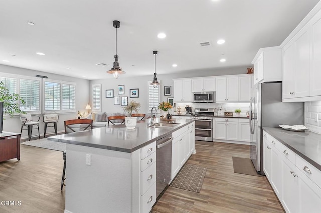 kitchen featuring hardwood / wood-style floors, sink, decorative light fixtures, a kitchen bar, and stainless steel appliances