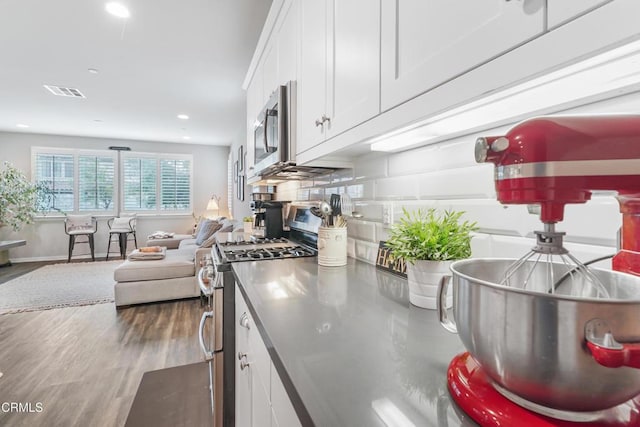 kitchen with dark hardwood / wood-style flooring, white cabinets, and stainless steel appliances