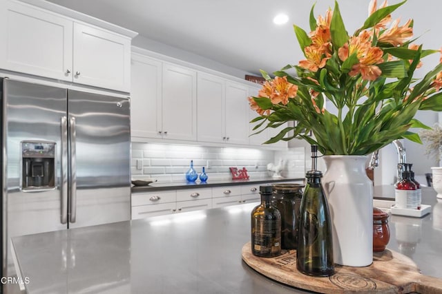 kitchen with decorative backsplash, stainless steel fridge, and white cabinets