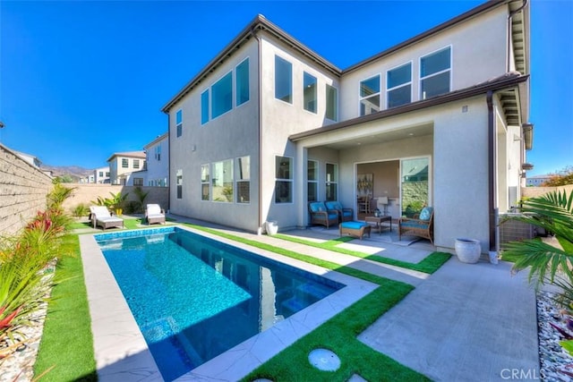 back of property with an outdoor living space, a fenced in pool, and a patio