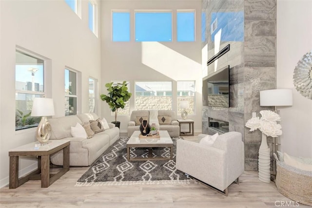 living room with a high ceiling, light hardwood / wood-style flooring, and a healthy amount of sunlight