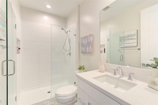 bathroom featuring vanity, toilet, and a shower with door