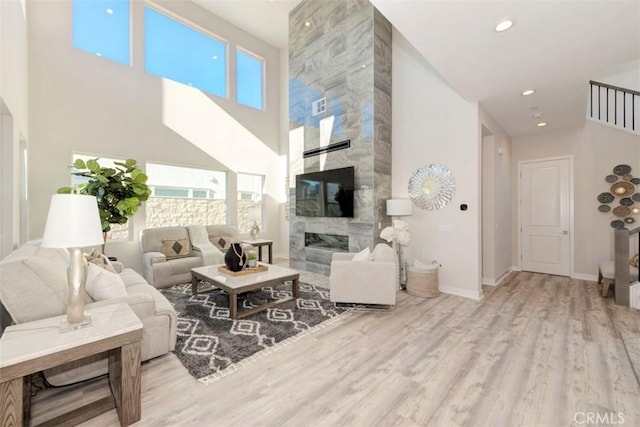 living room with plenty of natural light, a high ceiling, and light hardwood / wood-style flooring