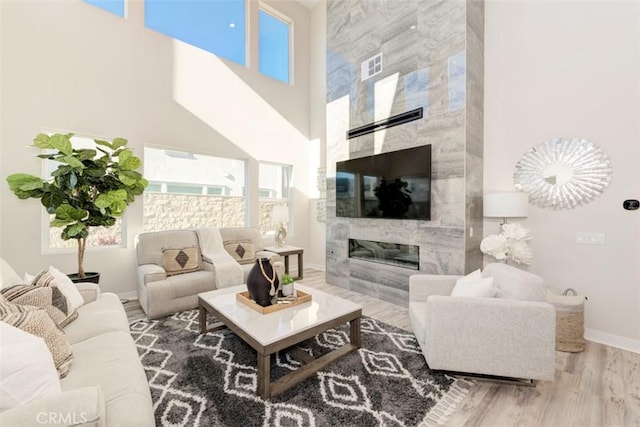 living room with hardwood / wood-style floors, a high end fireplace, and a high ceiling