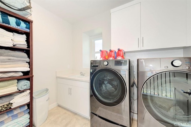 laundry room with cabinets, washing machine and dryer, and sink