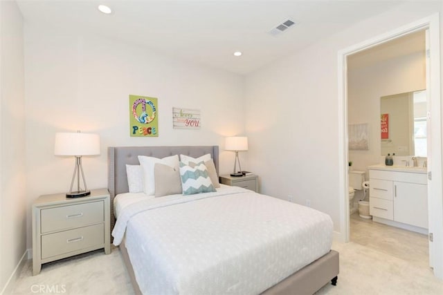 bedroom featuring ensuite bathroom, light colored carpet, and sink