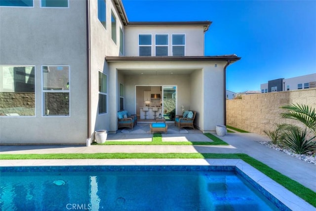 rear view of property featuring a fenced in pool, outdoor lounge area, and a patio