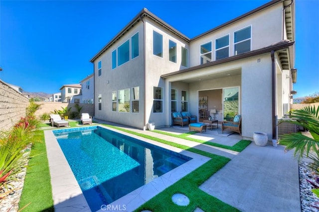 rear view of property featuring outdoor lounge area, a patio area, and a fenced in pool