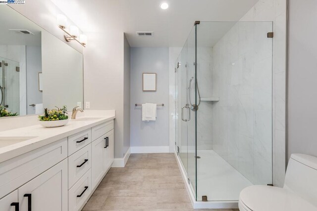 bathroom featuring toilet, an enclosed shower, vanity, and wood-type flooring