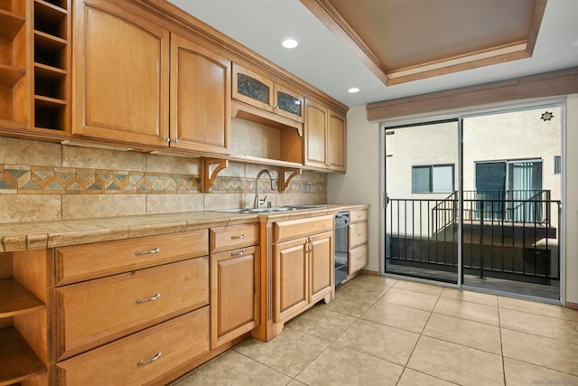 kitchen with sink, a raised ceiling, tile counters, decorative backsplash, and light tile patterned floors