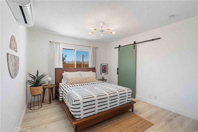 62044 Valley View Cir, Joshua Tree, CA 92252 - bedroom with a barn door, an AC wall unit, light wood-type flooring, and a chandelier