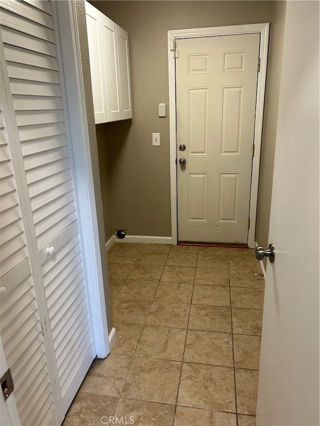 laundry area with light tile patterned floors and cabinets