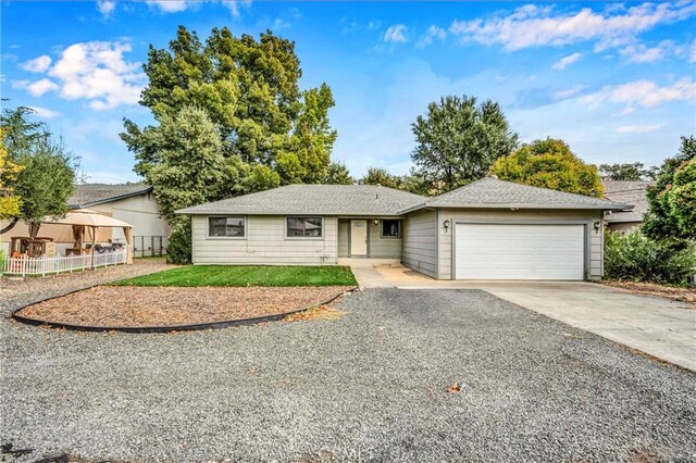 ranch-style house with a garage, driveway, and fence