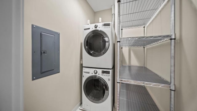 clothes washing area with electric panel and stacked washer / dryer