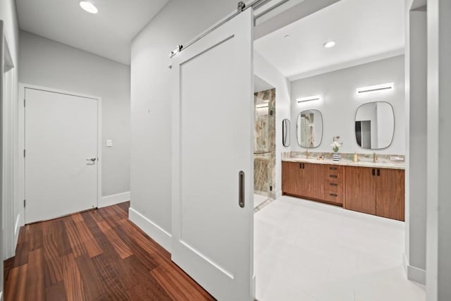 corridor featuring dark hardwood / wood-style floors, a barn door, and sink