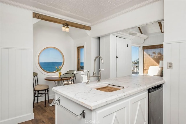 kitchen with a sink, light stone counters, dark wood-style floors, white cabinetry, and lofted ceiling