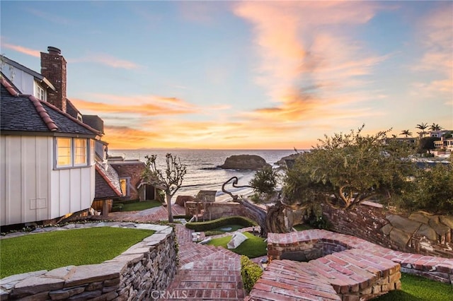 yard at dusk featuring a patio area and a water view