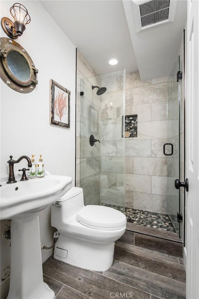 bathroom featuring visible vents, a shower stall, toilet, and wood finished floors