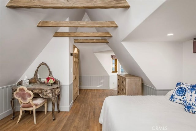 bedroom featuring vaulted ceiling with beams, wood finished floors, and wainscoting