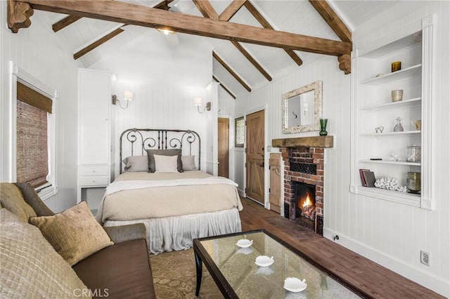 bedroom with a brick fireplace, wood finished floors, and vaulted ceiling with beams