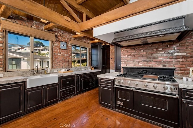 kitchen featuring custom range hood, light wood-type flooring, designer stove, vaulted ceiling with beams, and sink