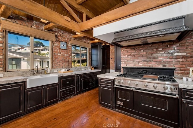 kitchen with light wood finished floors, brick wall, double oven range, range hood, and a sink