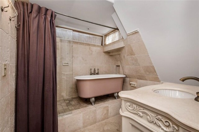 bathroom with tile walls, a bath, and vanity