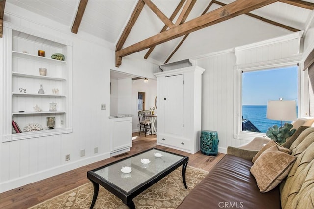 living room with built in shelves, hardwood / wood-style floors, vaulted ceiling with beams, and a water view