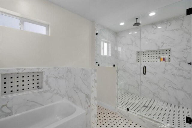 bathroom with plenty of natural light, tile walls, and independent shower and bath