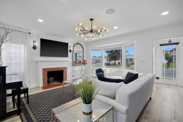 living room featuring a fireplace, a chandelier, and light wood-type flooring