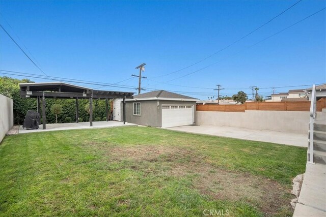 view of yard featuring a patio area, a garage, and an outdoor structure