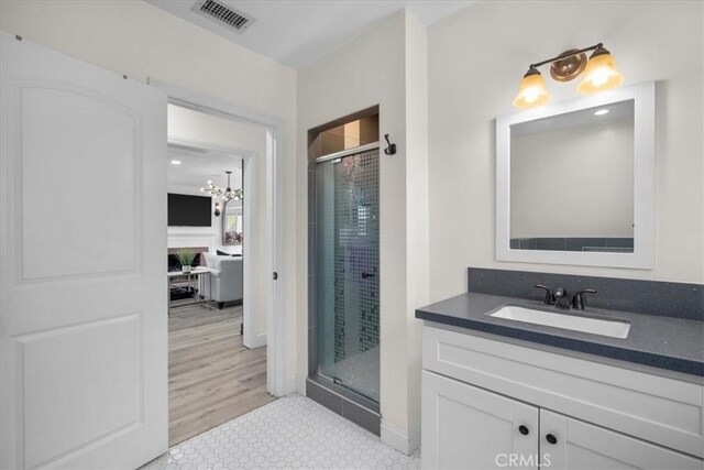 bathroom with vanity, wood-type flooring, a shower with door, and an inviting chandelier