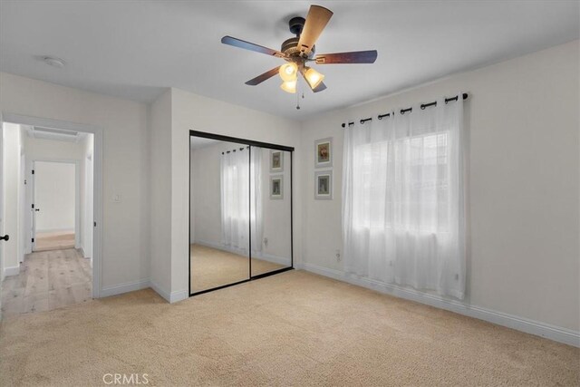 unfurnished bedroom with ceiling fan, light colored carpet, and a closet