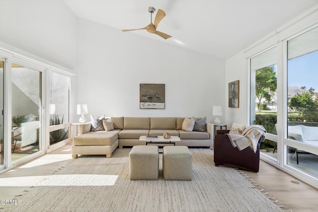 living room featuring ceiling fan, high vaulted ceiling, and light hardwood / wood-style flooring