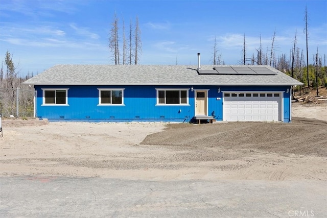 ranch-style home with solar panels and a garage