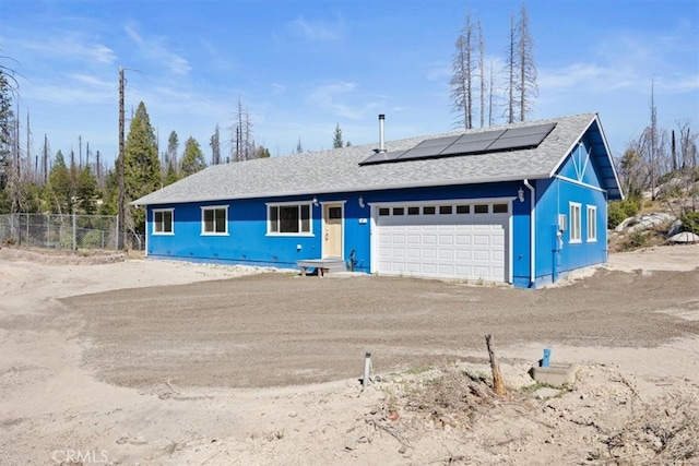 single story home featuring solar panels and a garage