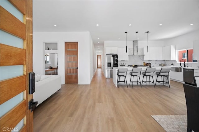 kitchen with a breakfast bar, stainless steel appliances, decorative light fixtures, white cabinets, and a center island