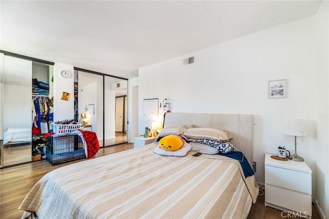 bedroom featuring hardwood / wood-style floors and multiple closets