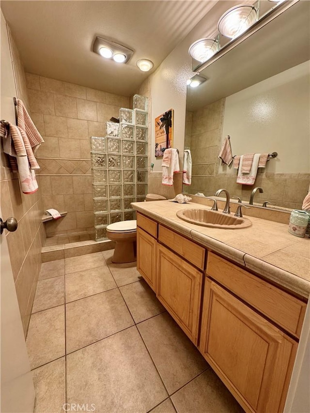 bathroom with vanity, a tile shower, tile patterned floors, and toilet