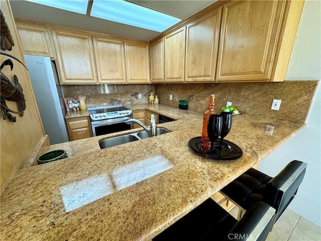 kitchen featuring appliances with stainless steel finishes, sink, a kitchen bar, kitchen peninsula, and light stone countertops