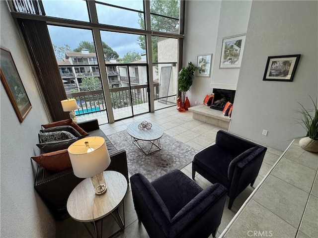 tiled living room with floor to ceiling windows, a tile fireplace, and a high ceiling