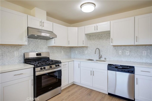 kitchen featuring stainless steel appliances, white cabinets, decorative backsplash, light hardwood / wood-style floors, and sink