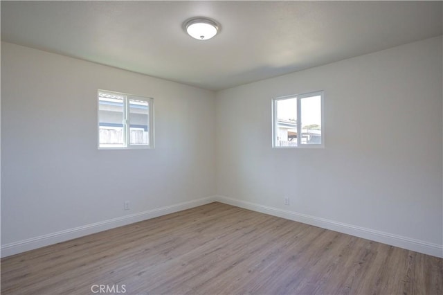 spare room featuring a healthy amount of sunlight and light hardwood / wood-style flooring