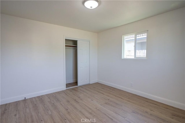 unfurnished bedroom with light wood-type flooring and a closet