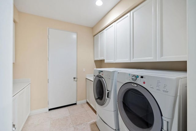 washroom with cabinets, light tile patterned floors, and washing machine and clothes dryer