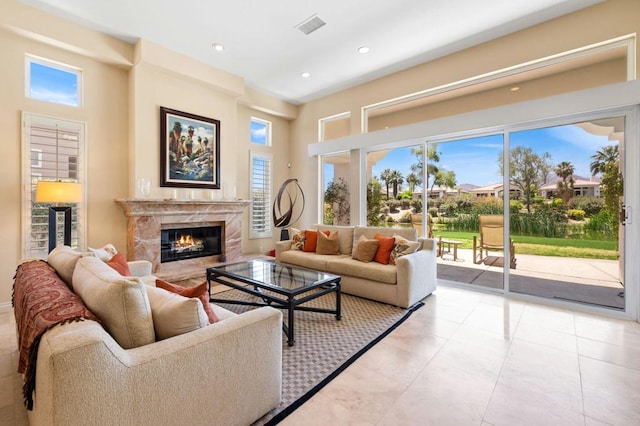 tiled living room featuring a premium fireplace and a towering ceiling