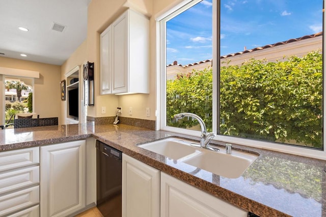 kitchen featuring sink, black dishwasher, kitchen peninsula, dark stone counters, and white cabinets