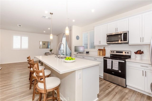 kitchen featuring white cabinets, an island with sink, pendant lighting, and appliances with stainless steel finishes