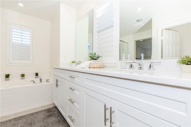 bathroom with tile patterned flooring, vanity, and tiled tub