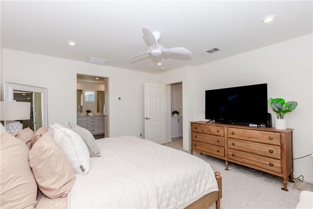 bedroom with light colored carpet, ceiling fan, and ensuite bathroom